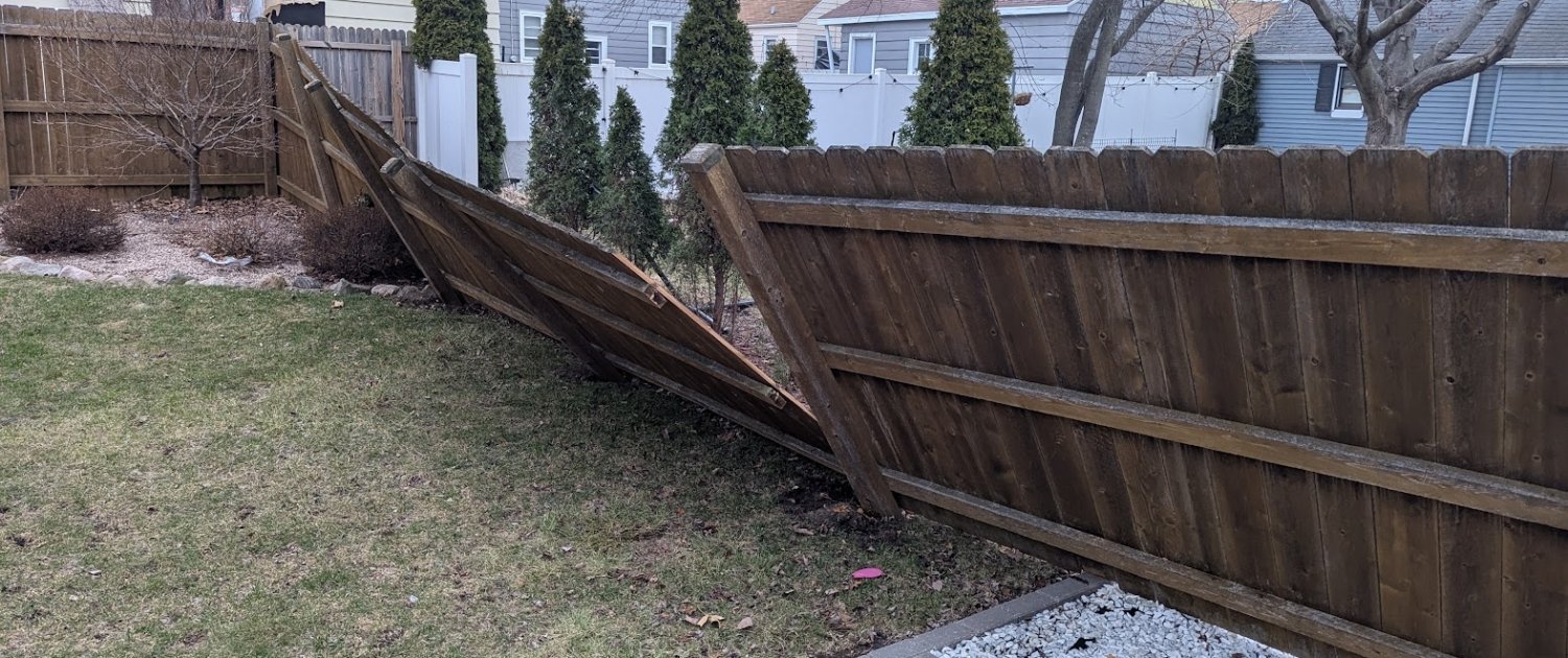 Damaged fence, with broken posts and torn pickets due to stormy winds