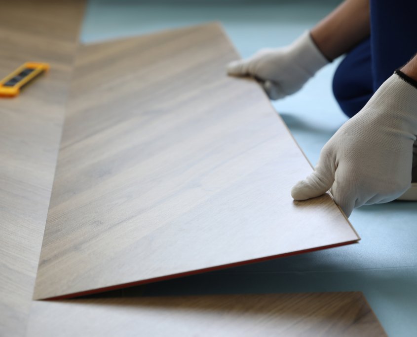 Worker installing laminated wooden floor indoors, closeup