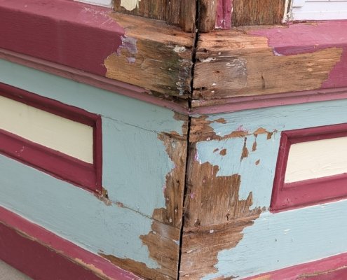 Rotten bay window frame A close-up view of severe wood rot, damage, and peeling paint along the exterior corner joint of a bay window frame.